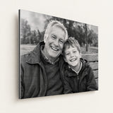 Zwart-witfoto op geborsteld aluminium met opa en kleinzoon, subtiele metaalstructuur