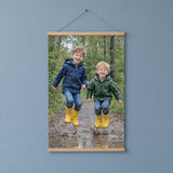 Foto op poster in een houten posterhanger met twee broertjes die in een plas springen